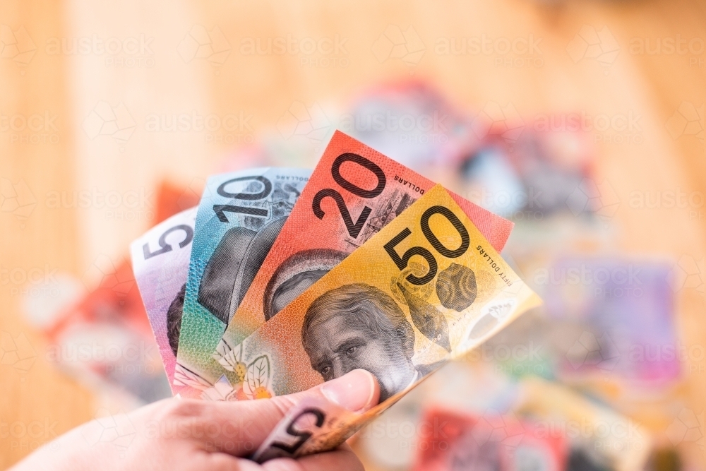 fanned out Australian money with more cash in the background - Australian Stock Image