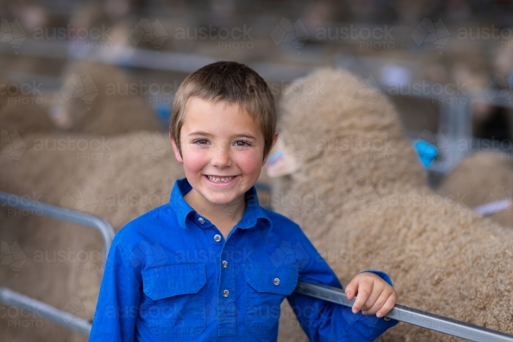 farm kid leaning on rails of sheep pens - Australian Stock Image