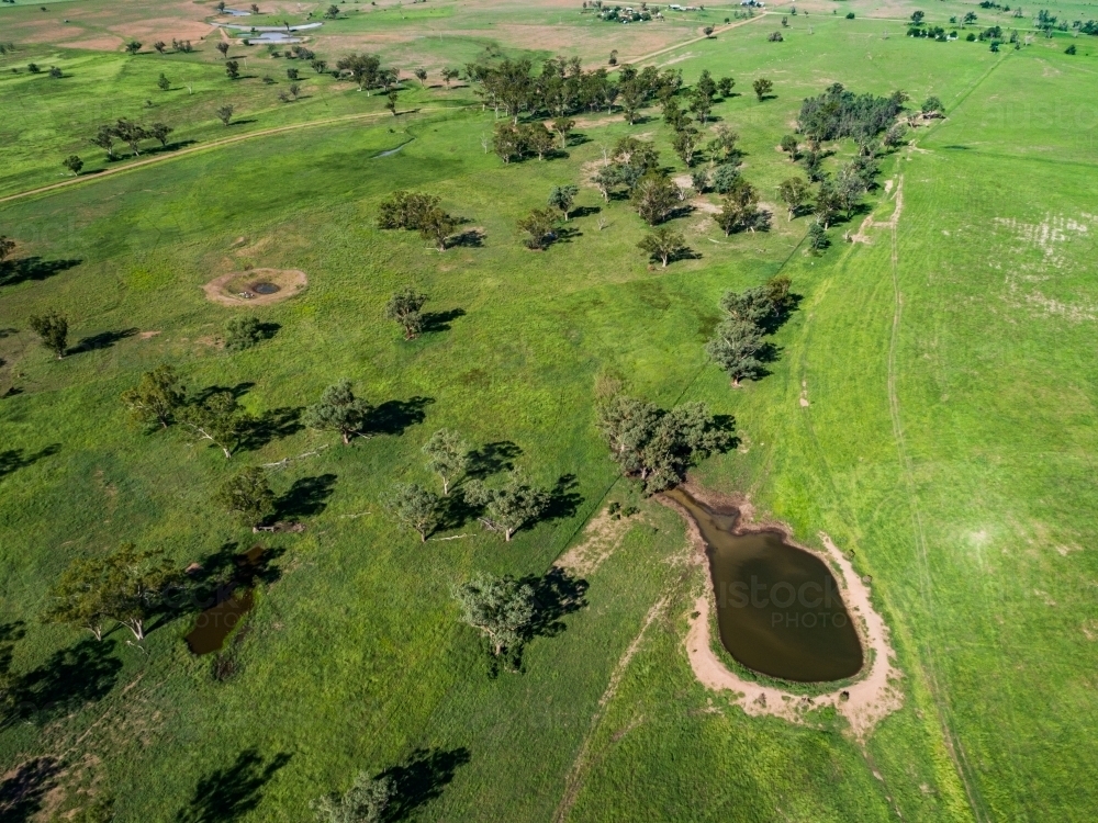 Farm landscape with dam and sunlit paddocks from the air - Australian Stock Image