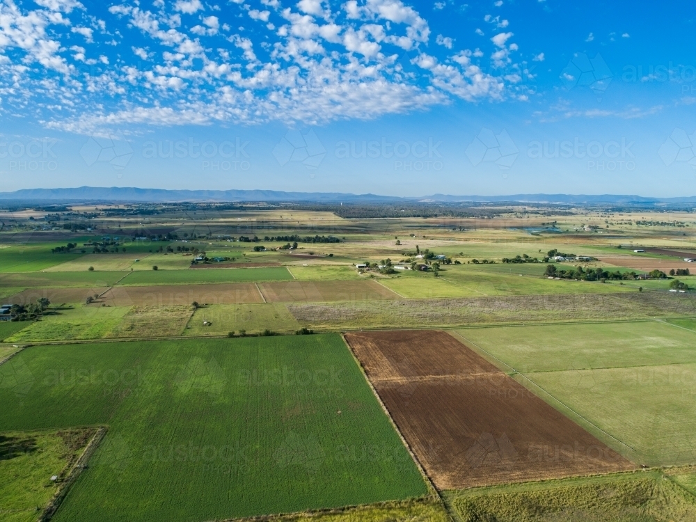 farm paddocks with distant highway leading out of town - Australian Stock Image