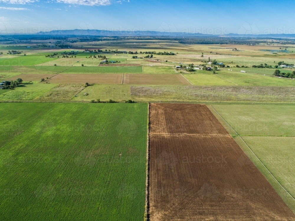 farm paddocks with distant highway leading out of town - Australian Stock Image