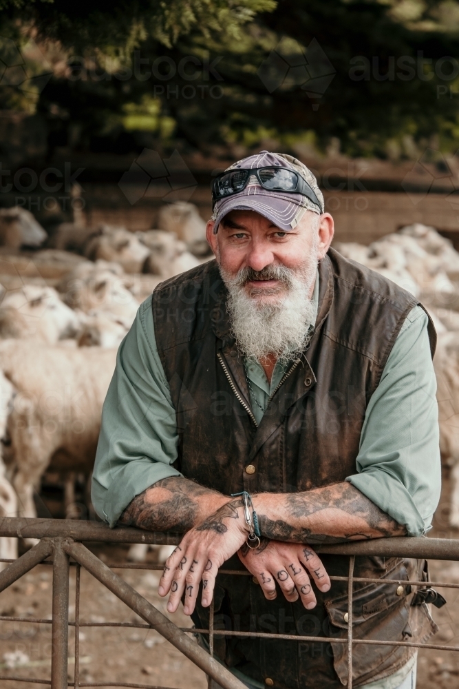 Farmer smiles at camera in sheep yards. - Australian Stock Image