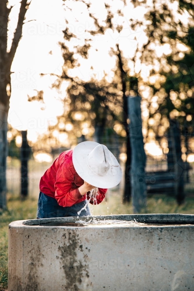 Farmer washing their face in the trough on farm - Australian Stock Image