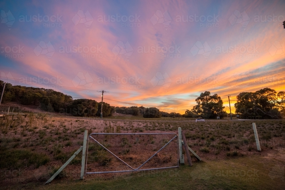 Farming gate in front of the coloured sunset sky. - Australian Stock Image