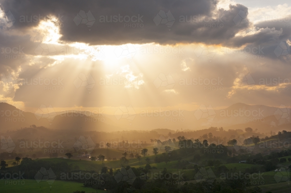 Farmland with golden sunlight shining through clouds - Australian Stock Image