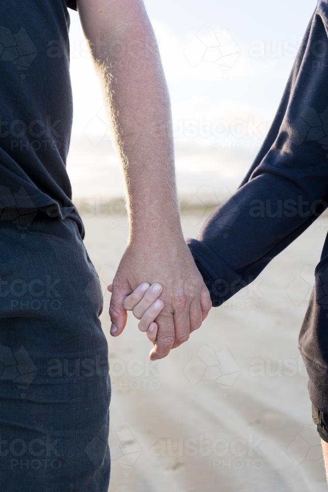 Father and daughter holding hands on the beach - Australian Stock Image