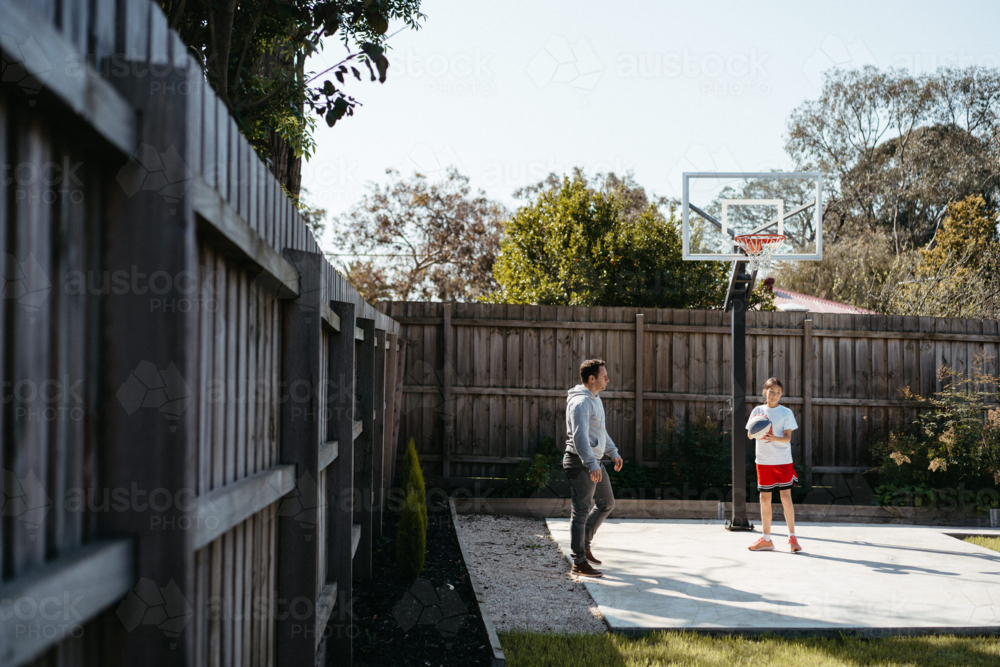 Father and daughter playing basketball in their yard - Australian Stock Image