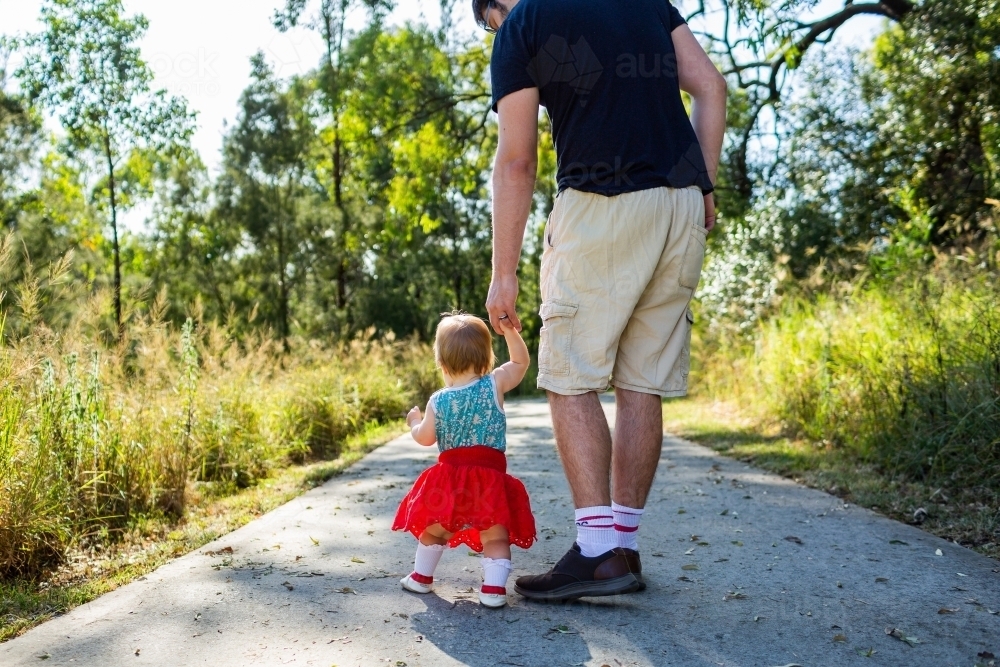 Father and daughter walking along path - toddler walk with parent - Australian Stock Image