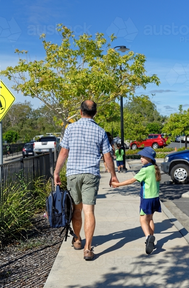 Father and daughter walking to school hand in hand - Australian Stock Image