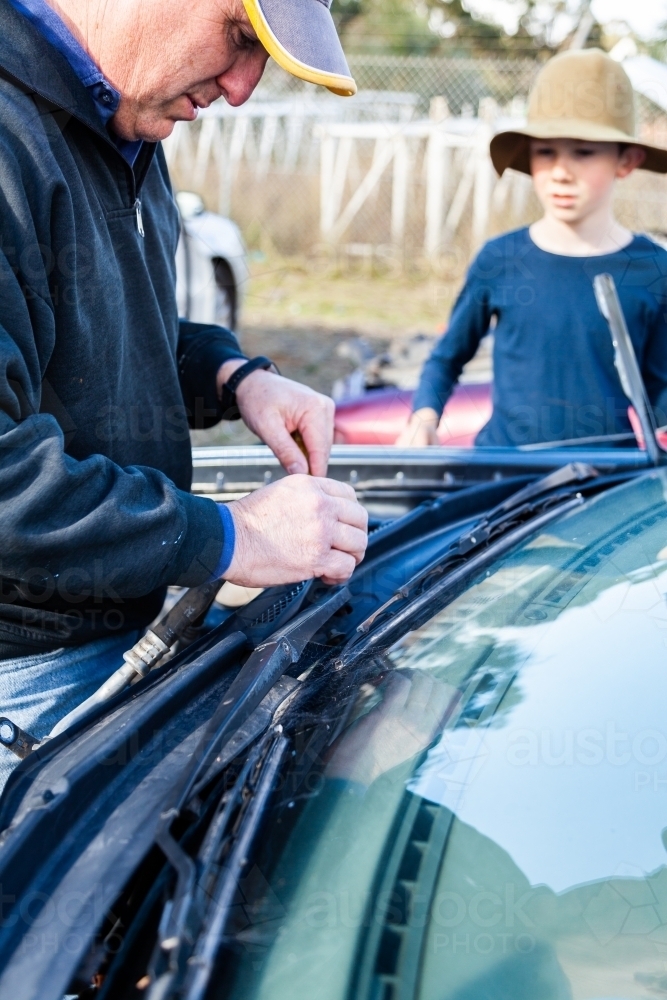 Father and son at wreckers pulling apart broken car for parts - Australian Stock Image