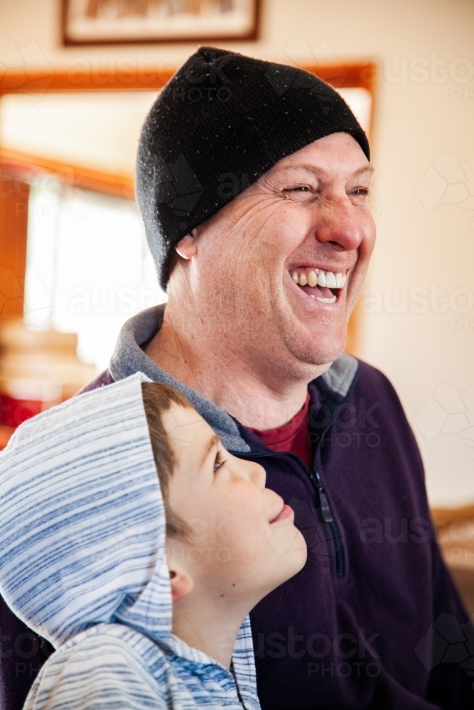 Father and son being silly and laughing together inside in winter - Australian Stock Image