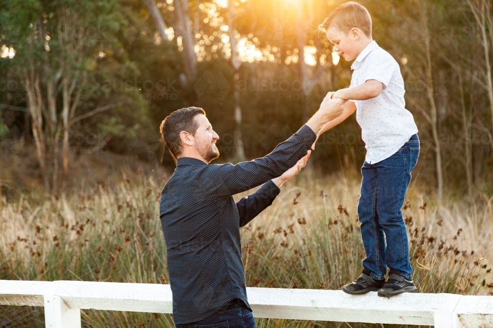 Father and Son holding hands balancing on the fence - Australian Stock Image