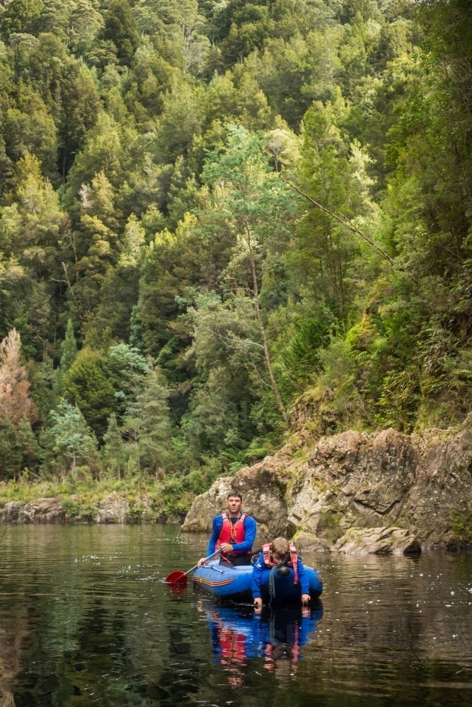 Father and son kayaking down tranquil lush river - Australian Stock Image