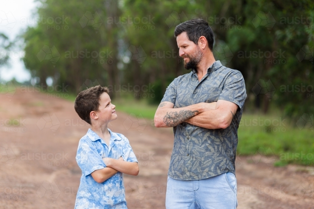 Father and son standing together outside with arms folded - Australian Stock Image