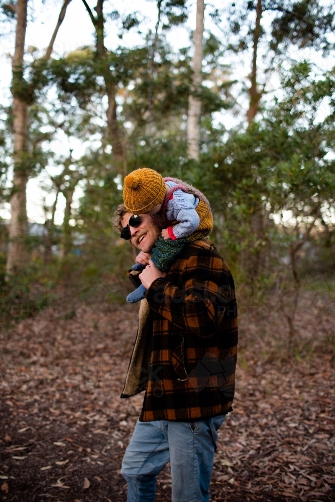 Father carrying toddler on shoulders in the bush - Australian Stock Image