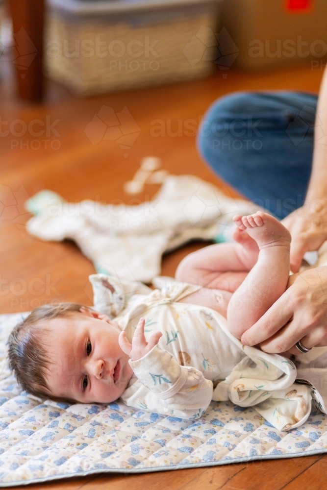 Father changing newborn baby's nappy on the floor - Australian Stock Image