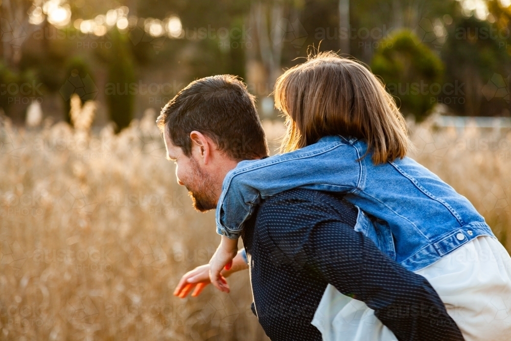 Father giving daughter a piggy back ride - Australian Stock Image