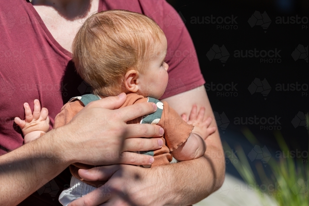 father hugging baby in sunlight - Australian Stock Image