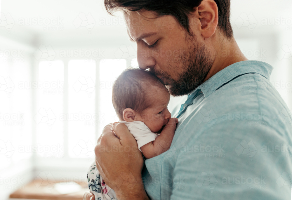 Father kissing newborn baby girls forehead - Australian Stock Image