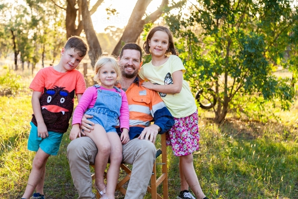 Father relaxing with three of his kids outside - Australian Stock Image