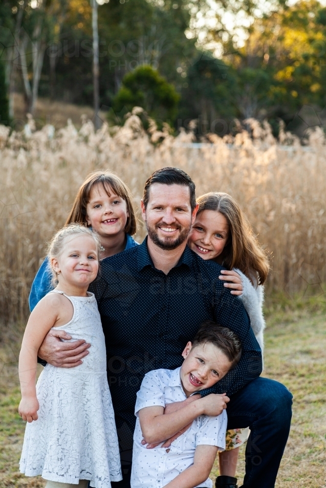 Father smiling of portrait with his four happy children - Australian Stock Image