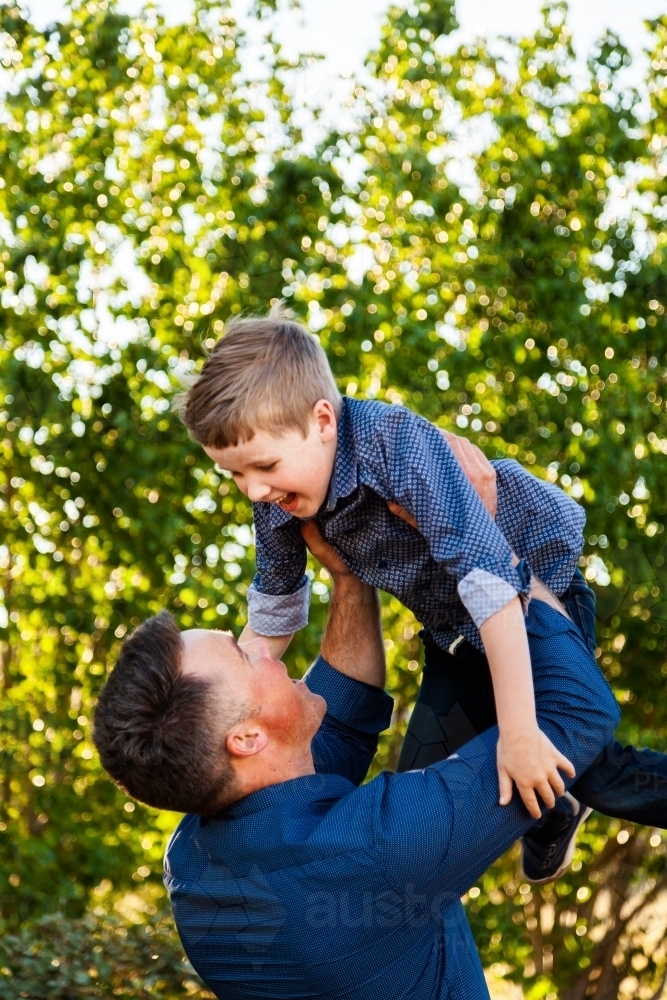 father throwing son in the air laughing - Australian Stock Image