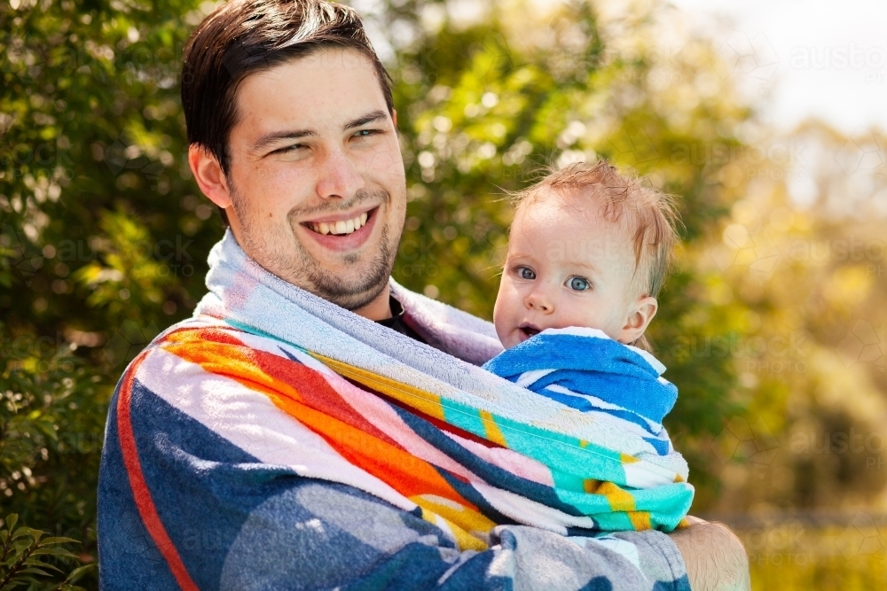 image-of-father-with-baby-wrapped-up-in-towel-after-swimming-in-pool-in