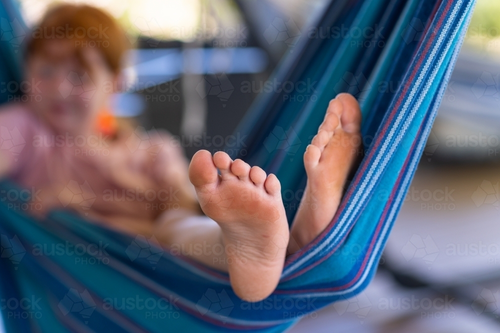 feet in focus of young girl relaxing in a hammock - Australian Stock Image