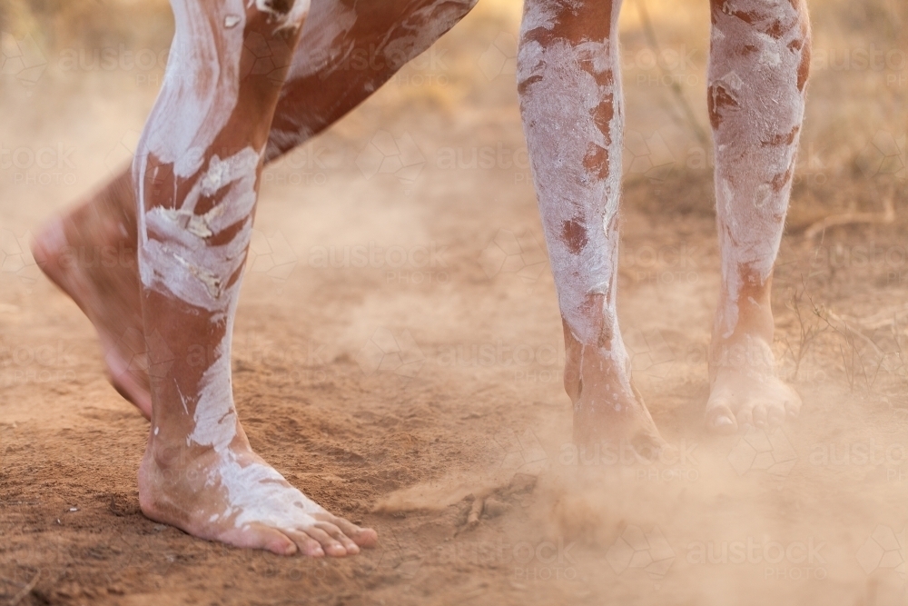 Feet of First nations people dancing in oka paint to tell the story kicking up dust - Australian Stock Image