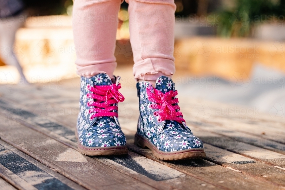 Feet only shot of little girl's bright boots with pink laces - Australian Stock Image