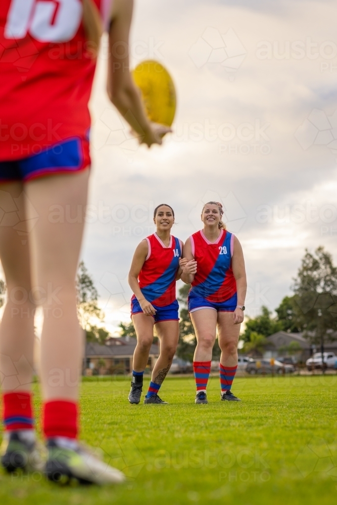 female aussie rules football players training in red and blue team uniforms - Australian Stock Image