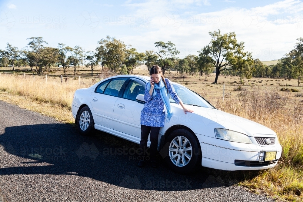 Female driver on phone beside car stopped on roadside in rural area - Australian Stock Image