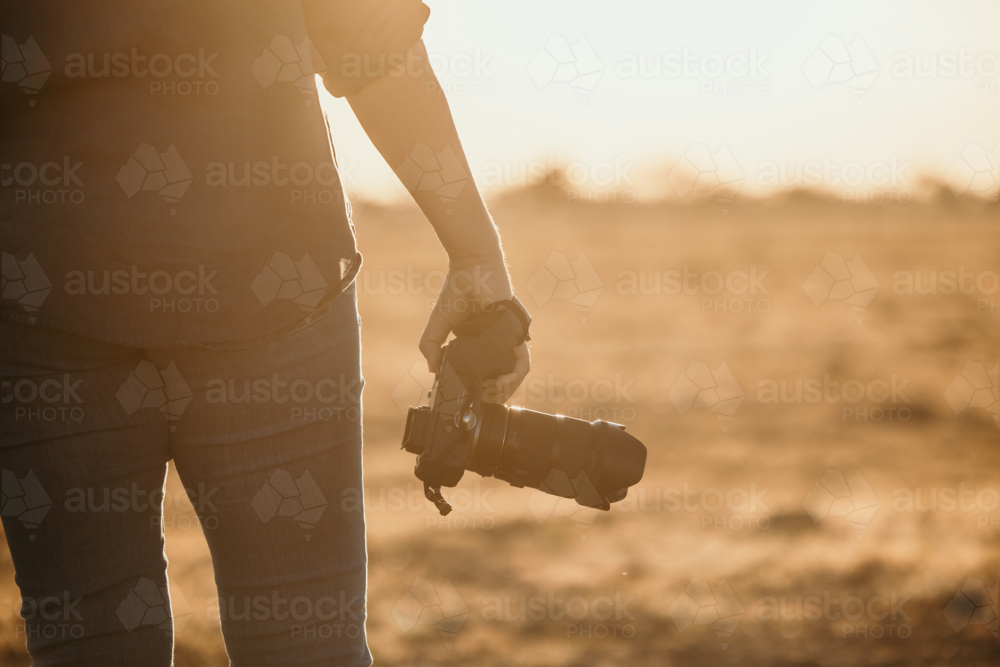 Female facing away holding camera beside body - Australian Stock Image