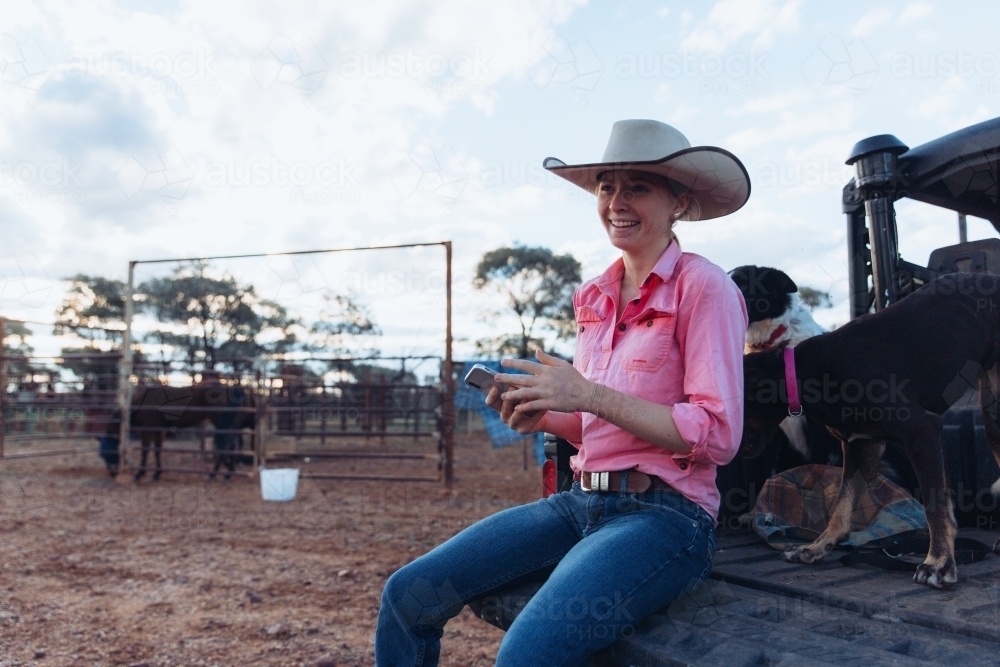 Female farmer sitting on the back of vehicle - Australian Stock Image