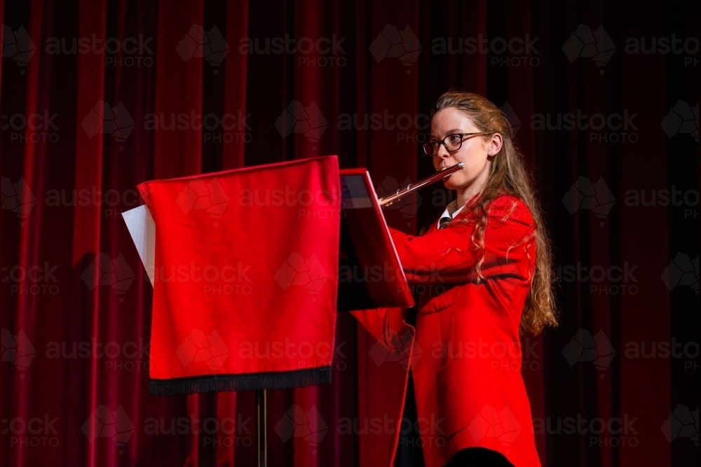 Female flautist playing solo performance on flute at concert - Australian Stock Image