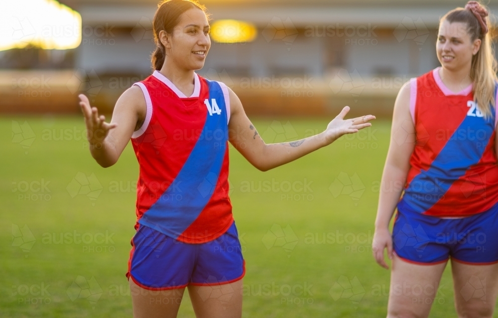 female football player gesturing with hands and arms while another player looks on - Australian Stock Image