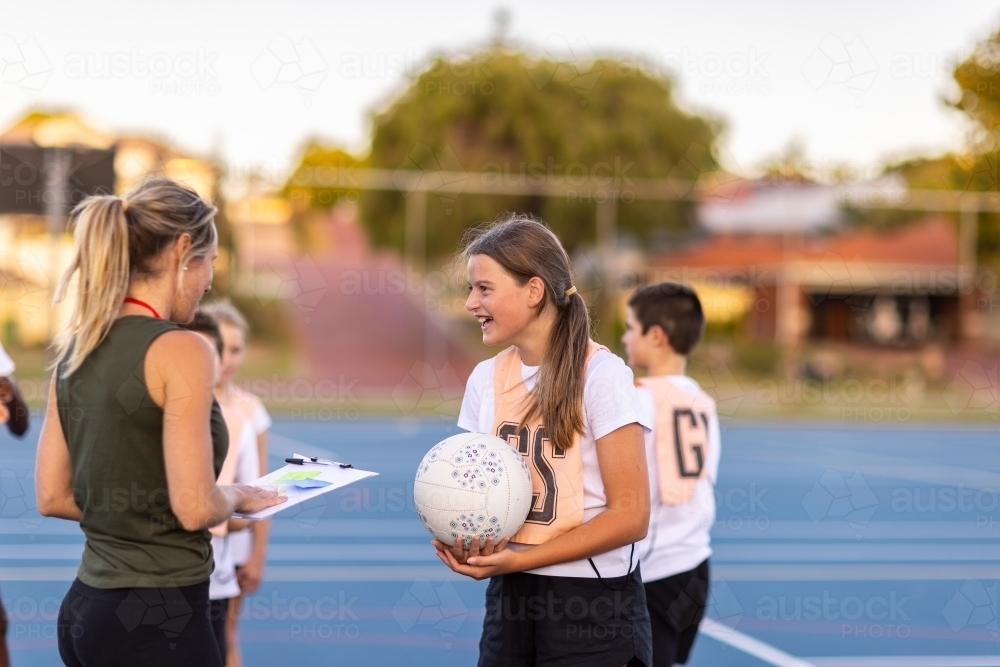 Image of female netball coach with a girl holding a netball on an ...