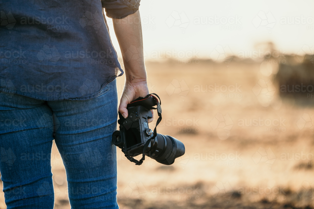 Female on farm holding camera facing away - Australian Stock Image