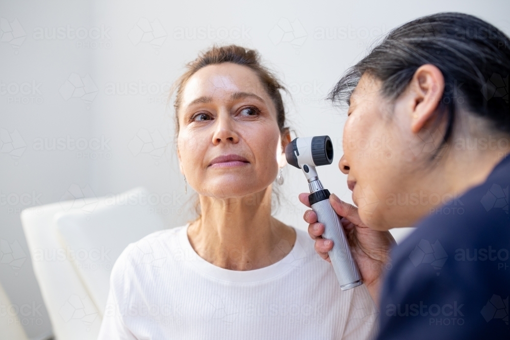 Female patient having her ears checked by a female nurse using an otoscope in the clinic - Australian Stock Image