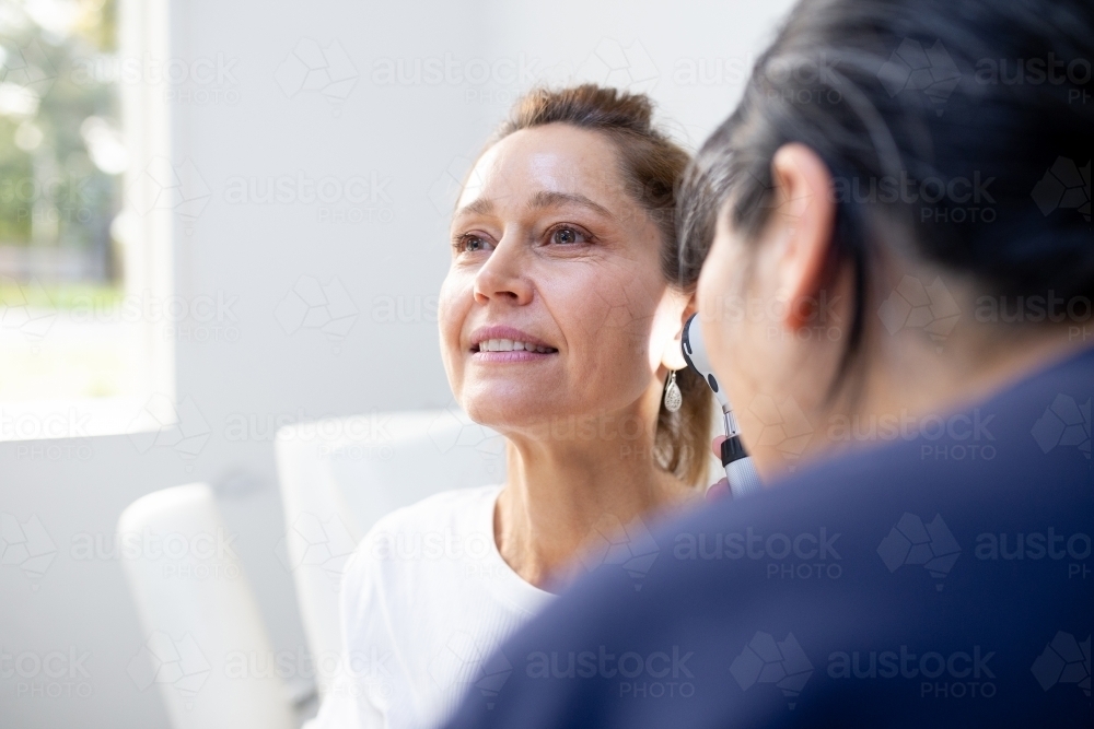 Female patient having her ears checked by a female nurse using an otoscope in the clinic - Australian Stock Image