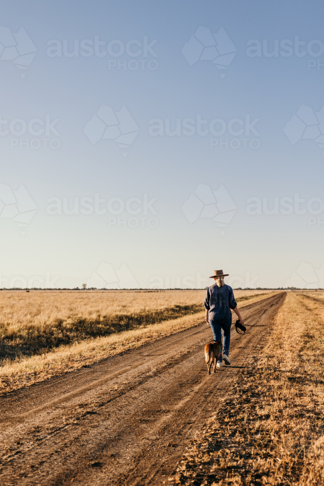 Female photographer walking along a road with dog - Australian Stock Image