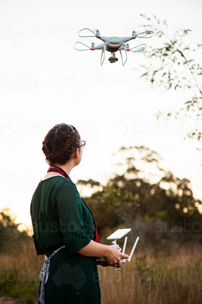 Female RPA pilot using a controller to fly a drone in rural area - Australian Stock Image