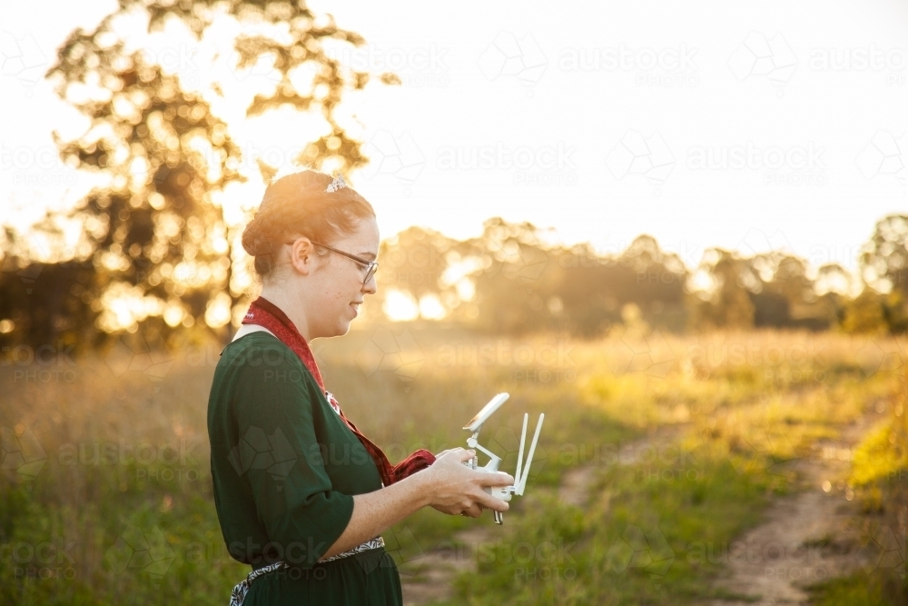 Female RPA pilot using a controller to fly a drone in rural area - Australian Stock Image