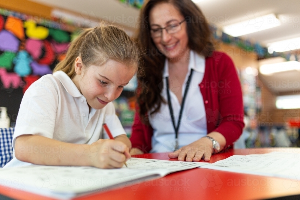 Female Teacher Helping Young Girl Write - Australian Stock Image