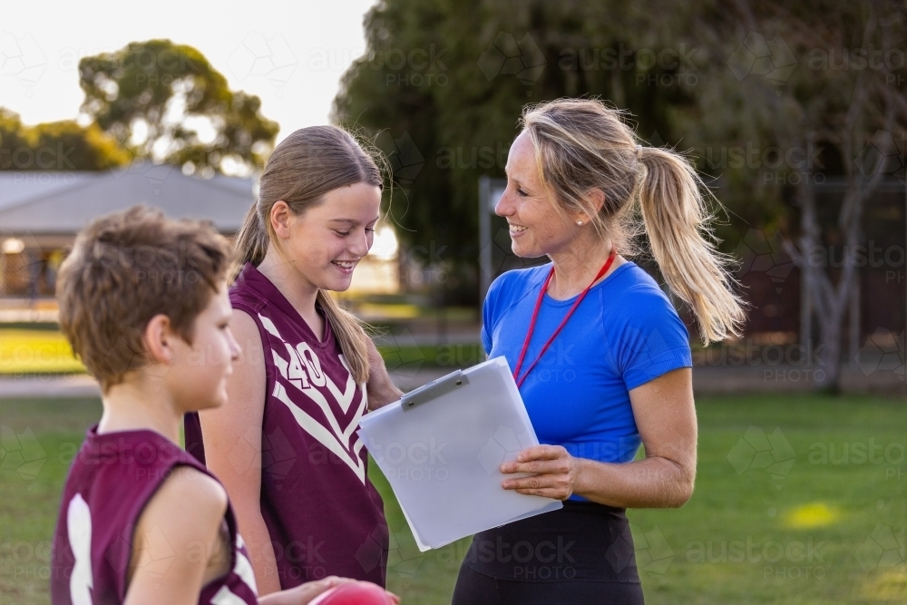 female teacher with two school children in sports uniform outdoors - Australian Stock Image