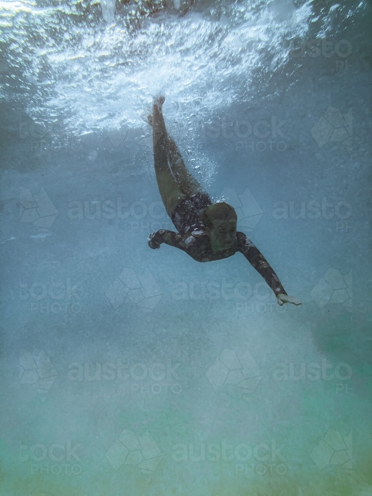 Female underwater in ocean wearing full piece swimsuit - Australian Stock Image