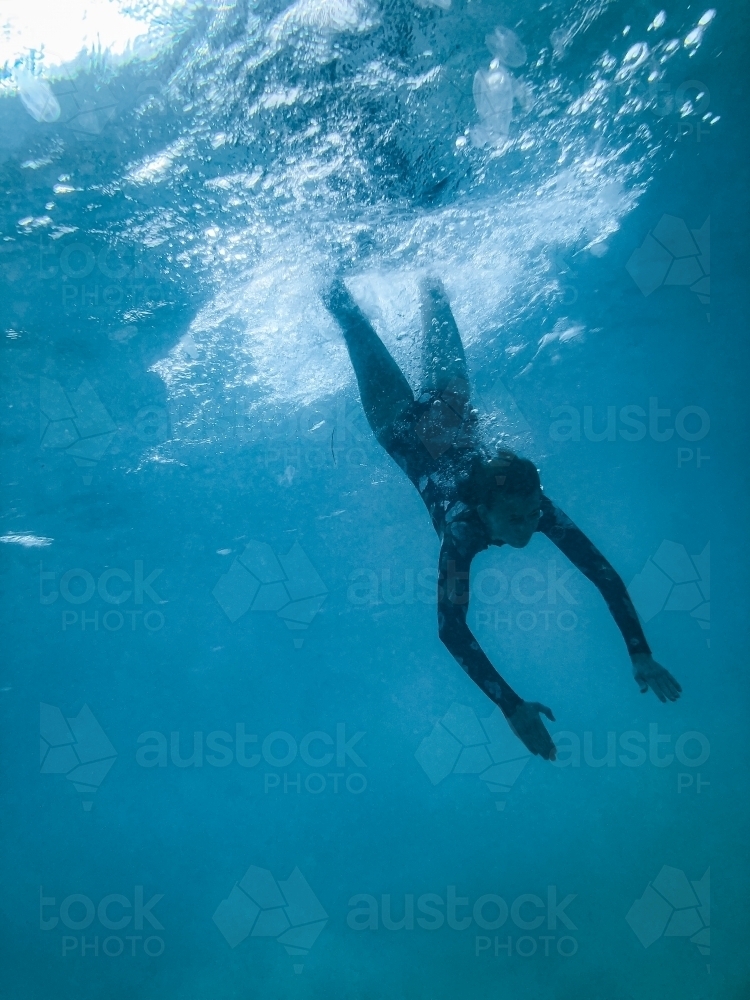 Female underwater in ocean wearing full piece swimsuit - Australian Stock Image