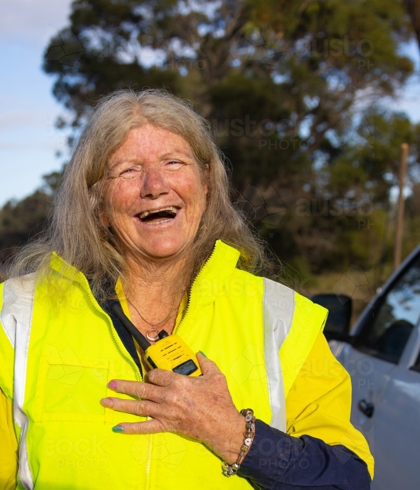 female worker outdoors wearing hi-vis and holding 2-way radio - Australian Stock Image