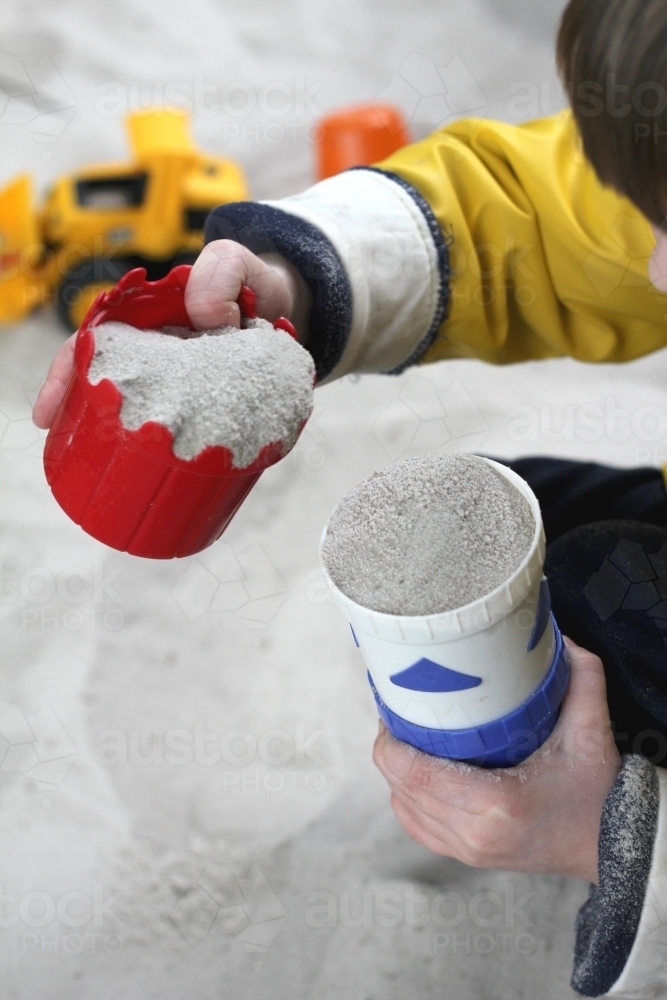 Filling cups with sand in sandpit - Australian Stock Image