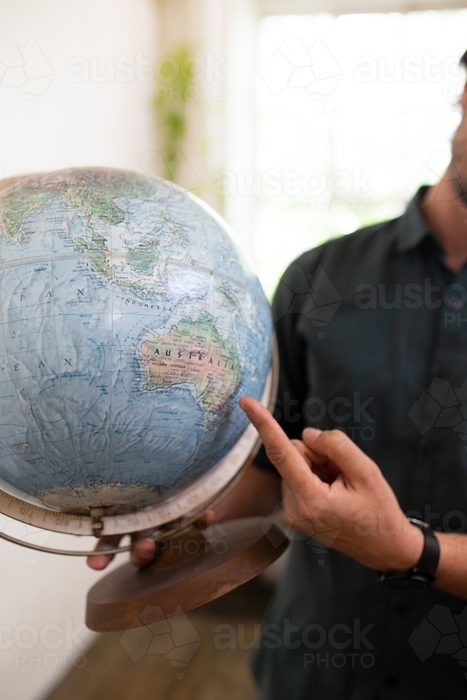 Finger pointing to map of Australia on round world globe - Australian Stock Image